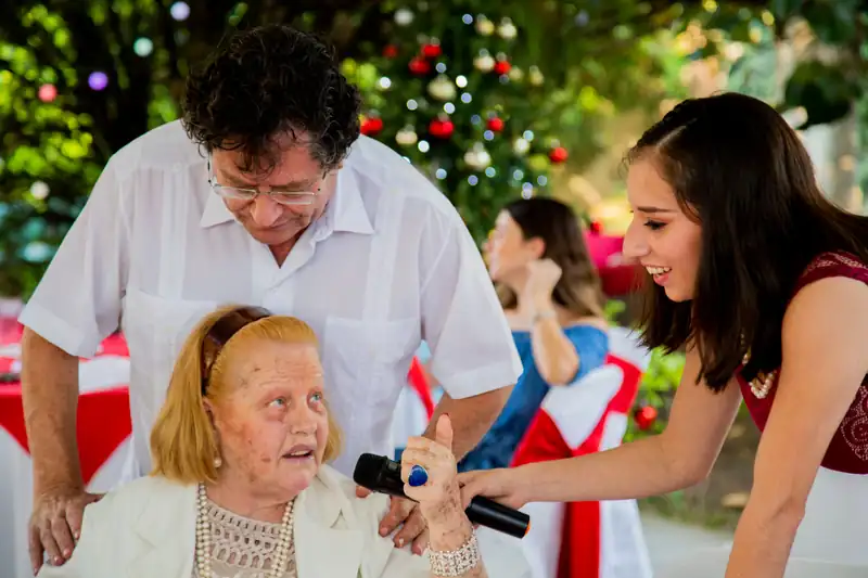 Adulto mayor cantando con micrófono en la fiesta navideña de Residencia Oasis Cuernavaca