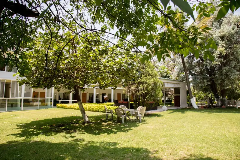 Jardín con árboles maduros y mesas al aire libre en la casa de retiro Oasis Cuernavaca