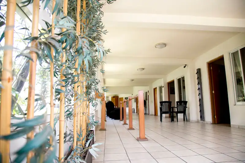 Pasillo exterior con pasamanos y acceso a las habitaciones en la casa de retiro Oasis Cuernavaca