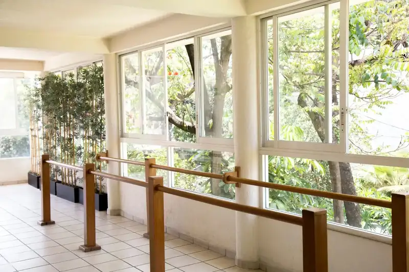 Barras paralelas de rehabilitación junto al ventanal con vista al jardín en Residencia Oasis Cuernavaca