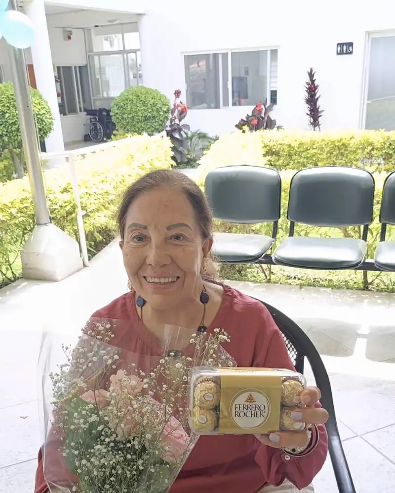 Residente sonriendo con un ramo de flores que le llevó su familia a Oasis Cuernavaca